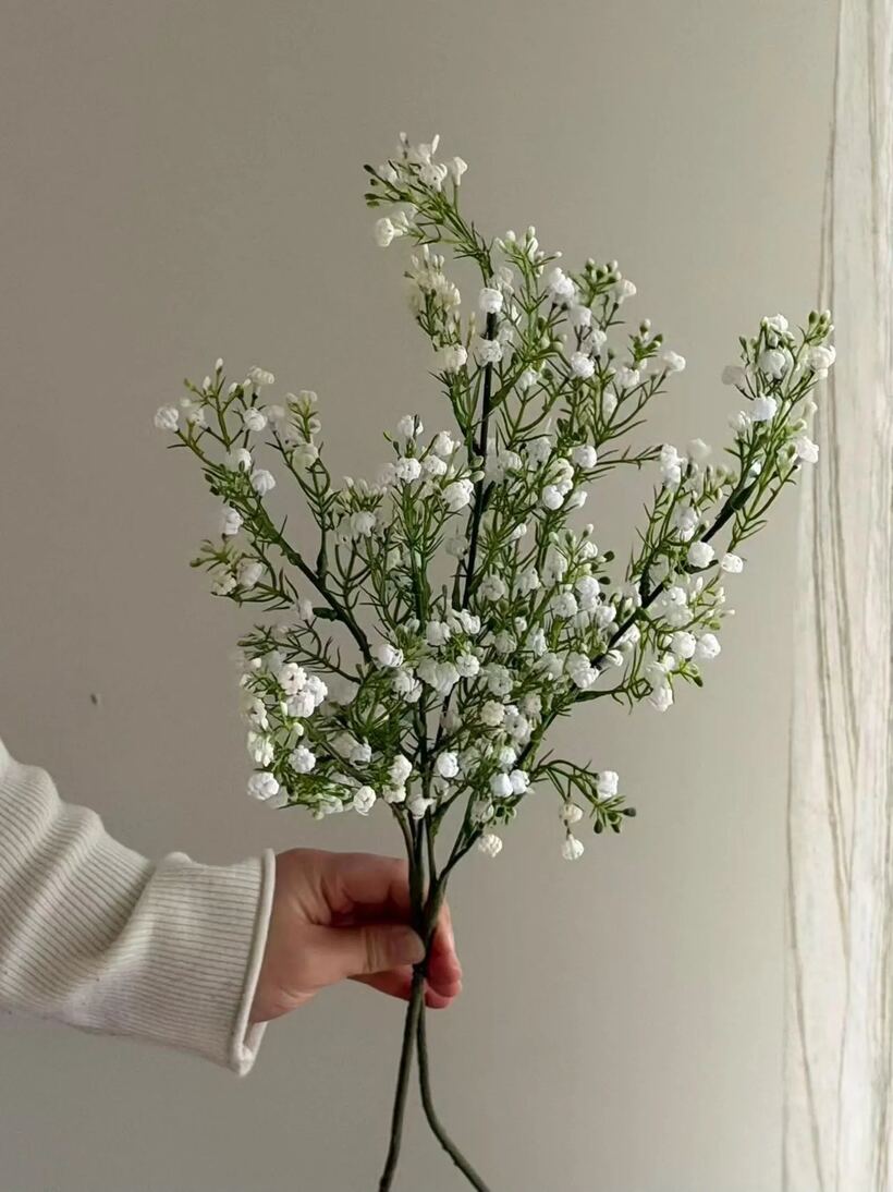 Hand holding a bundle of artificial white gypsophila stems