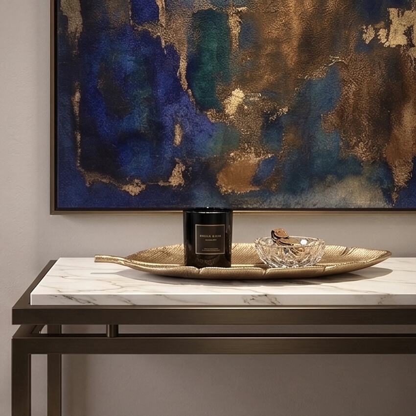 Gold leaf-shaped tray styled with a black candle and glass trinket dish on a marble console table